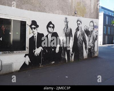 Un graffito bianco e nero sul muro del Cinema Pali con Blues Brothers, Kevin Costner, Indiana Jones, Jean Reno a Darmstadt, Germania Foto Stock