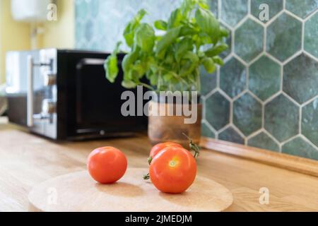 Pomodori freschi e basilico in interni cucina moderna con mobili bianchi sfondo casa Foto Stock