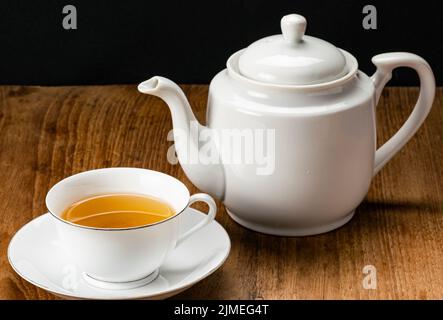 Vista su una tazza bianca in ceramica di tè caldo e bollitore per tè. Foto Stock