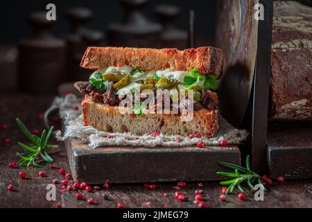 Sandwich piccante e gustoso con sottaceti, maiale tirato e salsa barbecue. Cucina americana. Foto Stock
