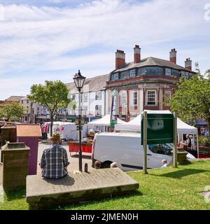 L'uomo sedette sulla lapide mangiando il pranzo al mercato settimanale che si tiene nella piazza della città a Poulton-le-fylde Foto Stock