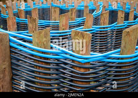 Recinzione di tubi di plastica intrecciata tra pali di legno. Foto Stock