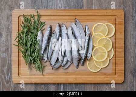 Spratti congelati su un tavolo da cucina con limoni e rosmarino Foto Stock