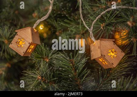 Sfondo invernale. Ghirlanda di alberi di Natale in forma di casette su un abete. Foto Stock