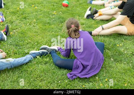 Ragazza adolescente siede sul prato verde. Ragazza nel parco. Riposa il giorno d'estate Foto Stock