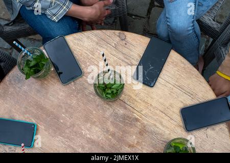 Gruppo di donne che hanno il loro smartphone giù su un tavolo mentre si gode un cocktail e compagnia. Donne online insieme. Vista dall'alto Foto Stock
