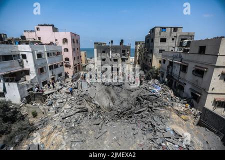 Città di Gaza, territori palestinesi. 06th ago 2022. I palestinesi ispezionano le rovine di un edificio crollato distrutto durante uno sciopero aereo israeliano. Sabato le forze di difesa israeliane hanno dichiarato che si stanno preparando per una "settimana di operazioni” contro i militanti palestinesi, in quanto da un giorno all'altro sono stati lanciati raffiche di razzi di rappresaglia da Gaza a seguito dell'uccisione mirata di un leader militante palestinese. Credit: Mohammed Talatene/dpa/Alamy Live News Foto Stock
