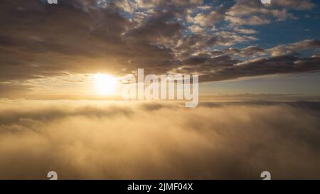 Vista aerea. Volare nella nebbia, volare nella nebbia sopra le nuvole del mattino presto nel sole che sorge. Ripresa da fotocamera aerea. Volo sopra il cl Foto Stock