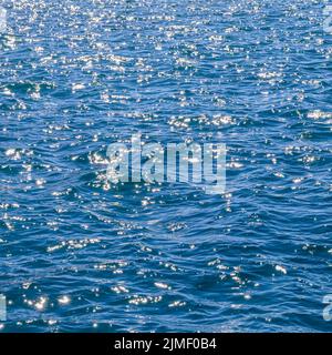 Le onde blu del mare al sole si illuminano come sfondo di superficie. Concetto di vacanza estiva Foto Stock