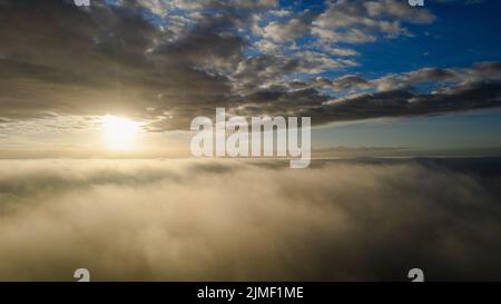 Vista aerea. Volare nella nebbia, volare nella nebbia sopra le nuvole del mattino presto nel sole che sorge. Ripresa da fotocamera aerea. Volo sopra il cl Foto Stock