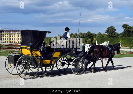Vienna, Austria - 01 agosto 2022: Turisti non identificati in una carrozza trainata da cavalli chiamata Fiaker e Palazzo di Schoenbrunn dal 18th secolo - ex Foto Stock