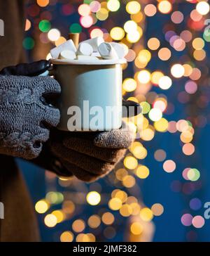 donna che tiene la tazza con vin brulé o cioccolata calda al mercatino di natale Foto Stock