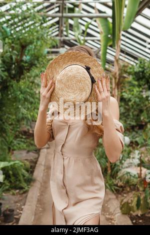 Una bella giovane donna si prende cura delle piante in una serra. Il concetto di giardinaggio e uno stile di vita ecologico. Foto Stock