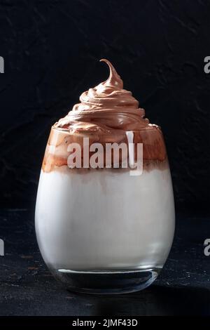 Caffè freddo Dalgona in un bicchiere su fondo nero. Trendy shake di latte coreano Foto Stock