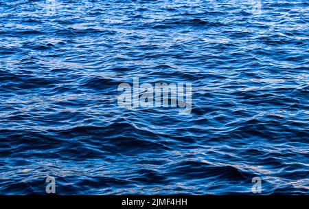Le onde blu del mare al sole si illuminano come sfondo di superficie. Concetto di vacanza estiva Foto Stock