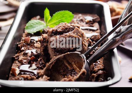 Gelato al cioccolato in vassoio di metallo con foglie di menta e noci di mandorla Foto Stock