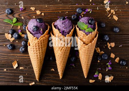 Vista piatta sui coni di cialda con BlackBerry icecream su tavolo da cucina in legno Foto Stock