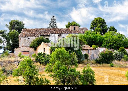 Antica casa di campagna in pietra abbandonata in Catalogna, circondata da un prato e alberi Foto Stock