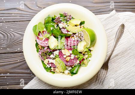 Vista superiore al mediterraneo barbabietole arrosto con insalata di avocado noci e formaggio feta origano e mash lascia sul tavolo per la cena Foto Stock