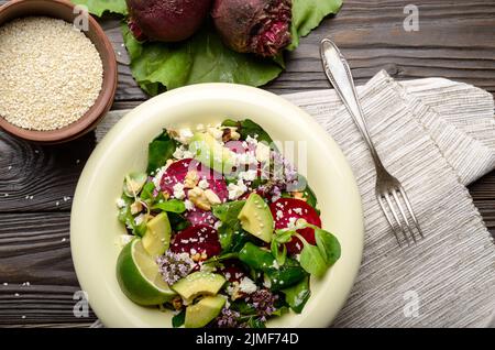 Vista superiore al mediterraneo barbabietole arrosto con insalata di avocado noci e formaggio feta origano e mash lascia sul tavolo per la cena Foto Stock