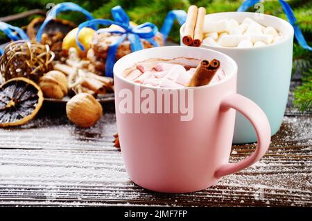 Sfondo di Natale di due tazze di cioccolata calda con marshmallows, ramo di abete rosso e vassoio con biscotti di pan di zenzero su t di legno Foto Stock