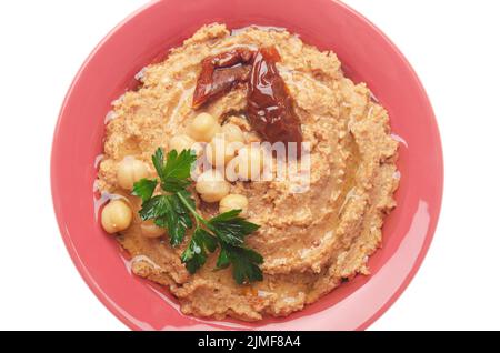 Vista piatta sull'hummus sormontato da fagioli, pomodori secchi e foglie di coriandolo verde isolate su sfondo bianco. Ritaglio Foto Stock