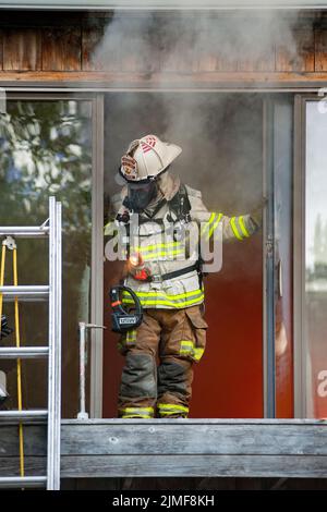 Un capo di Amagansett emerge dall'interno dell'edificio mentre il Dipartimento dei vigili del fuoco di Amagansett, insieme ai membri del Dipartimento dei vigili del fuoco di Montauk, tenne una vita Foto Stock