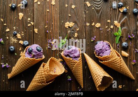 Vista piatta sui coni di cialda con BlackBerry icecream su tavolo da cucina in legno Foto Stock