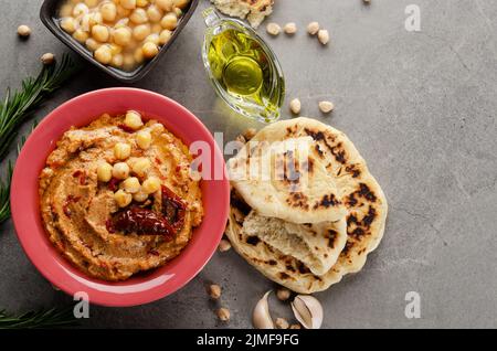 Appartamento Lay vista a Hummus in piatto di argilla sormontato con olio d'oliva, ceci e pomodori secchi al sole su tavolo di pietra servito con tradizionale Foto Stock