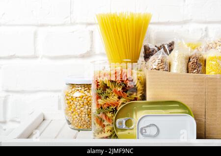 Set di cibi non cotti su scaffale di dispensa preparati per situazioni di emergenza disastro vista closeup Foto Stock