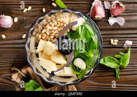 Ingredienti per la tradizionale salsa di pesto genovese italiana nel recipiente del robot da cucina. Vista piatta Foto Stock