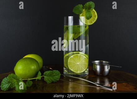 Un bicchiere di cocktail Mojito con menta e lime su un bordo nero Foto Stock