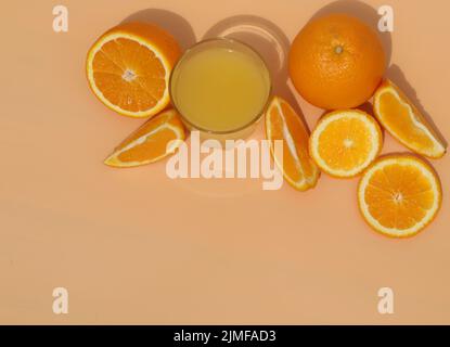 succo d'arancia fresco e luminoso con arance su sfondo giallo Foto Stock