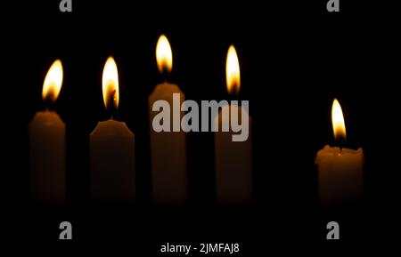 Cinque candele di Natale su uno sfondo scuro. Candele bruciate al buio Foto Stock