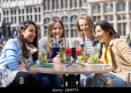 Anversa, Belgio, 21 maggio 2021, quattro donne di corsa mista turisti o studenti seduti fuori nel centro della città vecchia in un bar ter Foto Stock