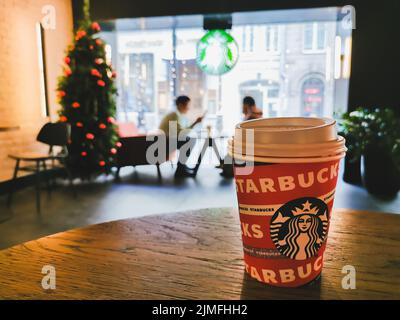 Una tazza di carta di caffè Starbucks su un tavolo in un bar. Foto Stock