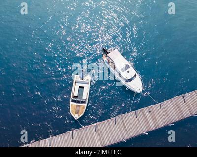 Barche vicino al molo sull'acqua. Acqua blu, mare e yacht Foto Stock