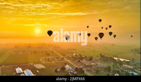 Vista aerea di molti palloni ad aria calda che volano al sole e al nebbia la mattina presto Foto Stock