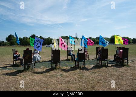 Runnymede, Surrey, Regno Unito. 6th Agosto 2022. Estinzione Rebellion Sud Est si accampavano al luogo di nascita della democrazia a Runnymede oggi, dove la Magna carta fu firmata oltre 800 anni fa. Presso il sito del National Trust, sedevano sulle proprie sedie giurate e sulle famose sedie in bronzo scolpite dei 12 giurati. Andarono anche al Magna carta Memorial. I bambini stavano facendo stampe murali e chiacchieravano con i membri del pubblico sulla loro campagna di disobbedienza civile e invitavano il governo ad agire con urgenza sull'emergenza climatica. Credit: Maureen McLean/Alamy Live News Foto Stock