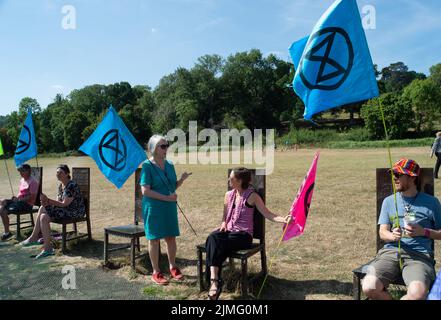 Runnymede, Surrey, Regno Unito. 6th Agosto 2022. Estinzione Rebellion Sud Est si accampavano al luogo di nascita della democrazia a Runnymede oggi, dove la Magna carta fu firmata oltre 800 anni fa. Presso il sito del National Trust, sedevano sulle proprie sedie giurate e sulle famose sedie in bronzo scolpite dei 12 giurati. Andarono anche al Magna carta Memorial. I bambini stavano facendo stampe murali e chiacchieravano con i membri del pubblico sulla loro campagna di disobbedienza civile e invitavano il governo ad agire con urgenza sull'emergenza climatica. Credit: Maureen McLean/Alamy Live News Foto Stock