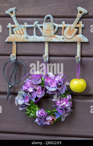 corona di fiori viola di hydrangea appesi sul binario del gancio del giardino Foto Stock