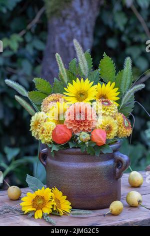 bouquet di dahlias arancione e giallo e girasoli in vecchio vaso di argilla Foto Stock