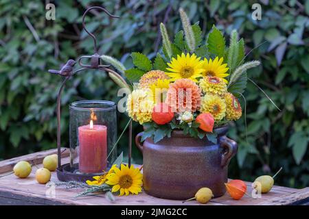 bouquet di dahlias arancione e giallo e girasoli in vecchio vaso di argilla Foto Stock