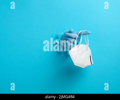 La mano femminile contiene una maschera medica monouso bianca per proteggere contro i virus durante un'epidemia e pandemia. Parte del corpo s Foto Stock