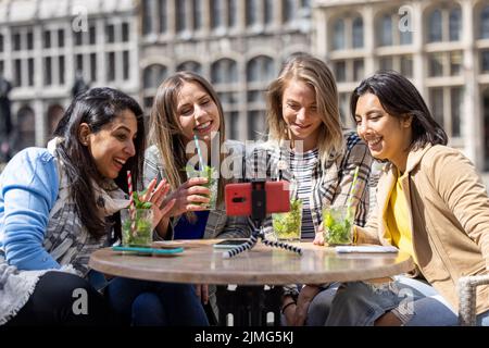 Anversa, Belgio, 21 maggio 2021, quattro amici multietnici, turisti o studenti seduti in una caffetteria sulla terrazza della città Foto Stock