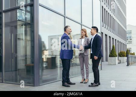 Incontro d'affari, colleghi il team felice si riunisce fuori ufficio, saluto mani agitate, diversi dipendenti in tuta aziendale, uomini e donne uomini d'affari Foto Stock