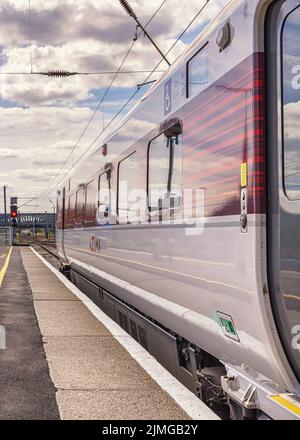 Un carro ferroviario poggia accanto a una piattaforma mentre si prepara a partire. Una porta è in primo piano e una luce di segnalazione è in distanza. Foto Stock