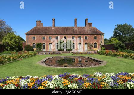 Un laghetto lilly circondato da un lussureggiante prato verde e fiori colorati nel terreno di una vecchia casa di campagna inglese Foto Stock