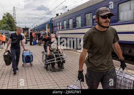 Volontari e un ufficiale di polizia assistono una vecchia signora in sedia a rotelle a bordo del treno di evacuazione alla stazione ferroviaria di Pokorvsk, Donetsk. In mezzo ai combattimenti intensificati nella parte orientale dell'Ucraina, l'Ucraina orientale sta ora intensificando la sua evacuazione civile, poiché milioni di famiglie ucraine stanno evacuando dalla guerra più stretta e stretta, poiché molte di esse saranno ricollocate nella parte occidentale del paese. Secondo le Nazioni Unite, almeno 12 milioni di persone sono fuggite dalle loro case dopo l'invasione russa dell'Ucraina, mentre sette milioni di persone sono sfollate all'interno del paese. Foto Stock