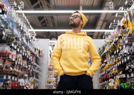 un uomo in un negozio di hardware esamina l'assortimento di merci sugli scaffali Foto Stock